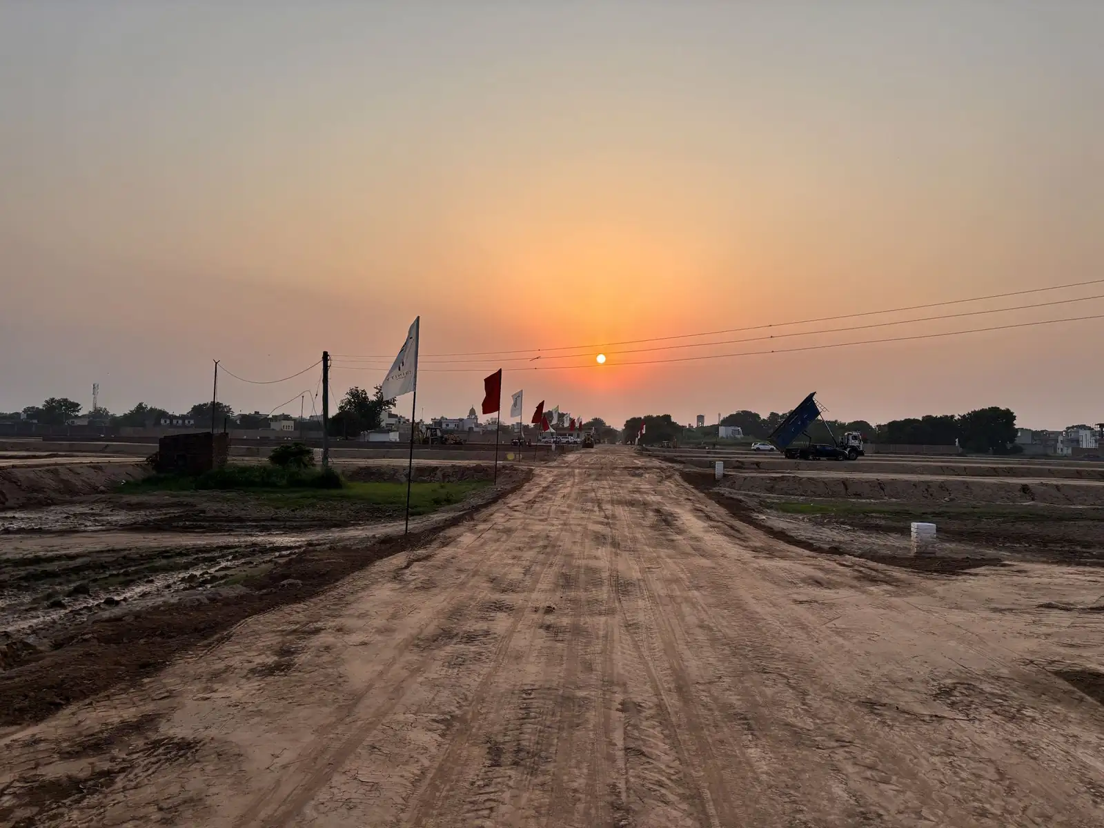Central road of The Ridge, Kurali with project flags at dusk